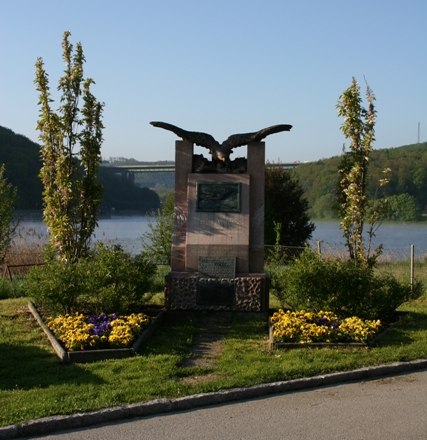 Denkmal von Wilhelm Kress in Tullnerbach vor einem See.
