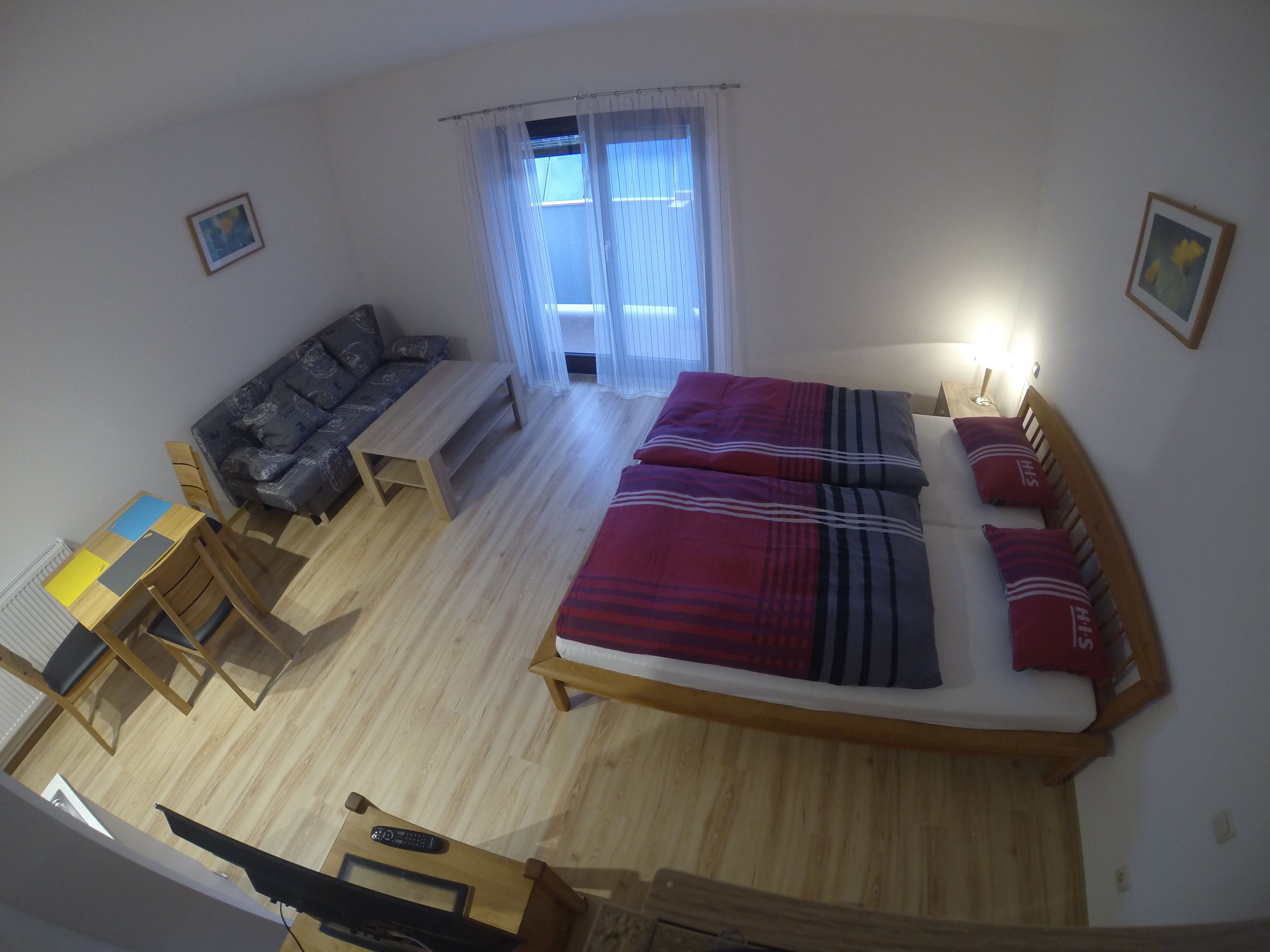 Ein einfach eingerichtetes Apartment mit Bett, Sofa, Tisch und Stühlen.