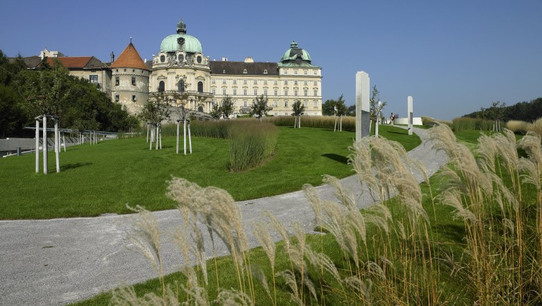Schloss mit grünem Dach, umgeben von gepflegtem Garten und Gehweg.