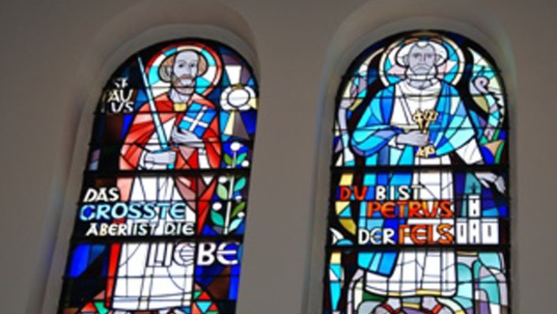 Two colorful stained glass windows with religious figures and inscriptions.