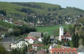 Panorama von Gablitz mit Kirche und umliegenden Häusern vor bewaldeten Hügeln.