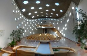 Moderner Kircheninnenraum mit runden Fenstern und Holzmöbeln.