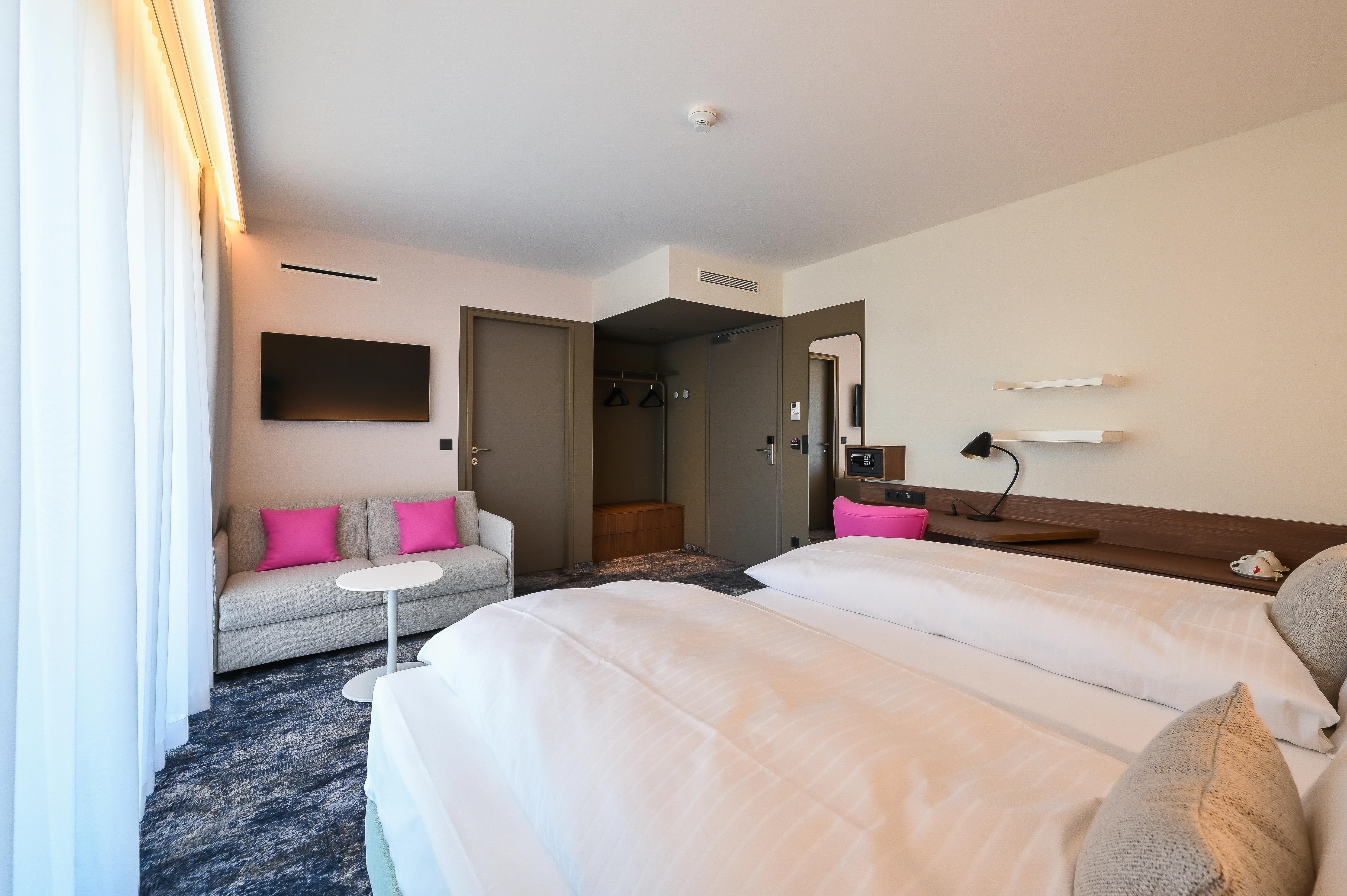 Moderne Hotelsuite mit Doppelbett, Sofa, Fernseher und Schreibtisch.