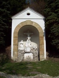 Eine kleine Kapelle mit einem Kreuz und religiösen Figuren in einer Nische.