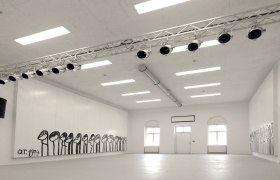 Innenansicht eines weißen Raumes mit Wandmalereien und Beleuchtung.