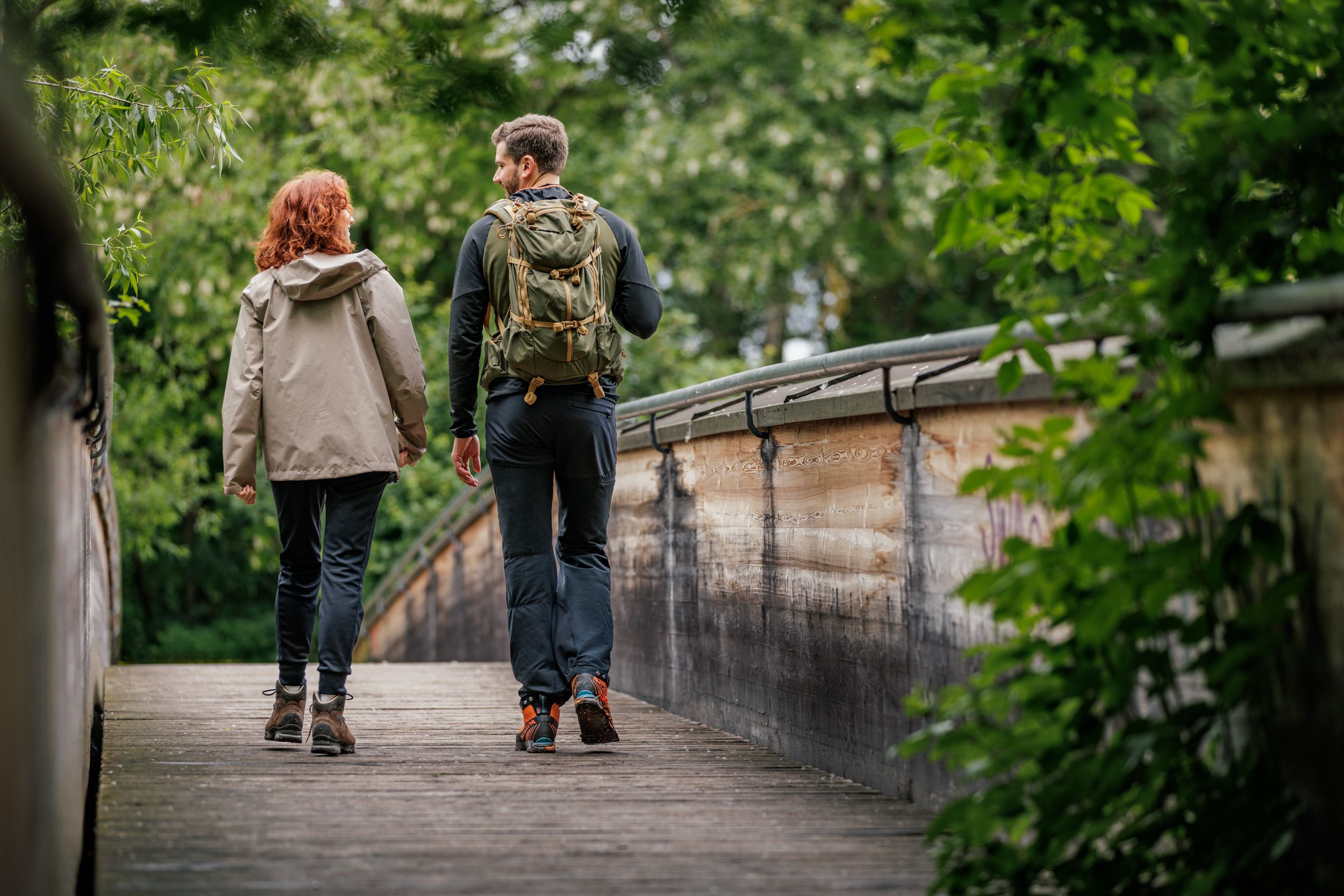 Zwei Wandernde auf einer Holzbrücke im Wald