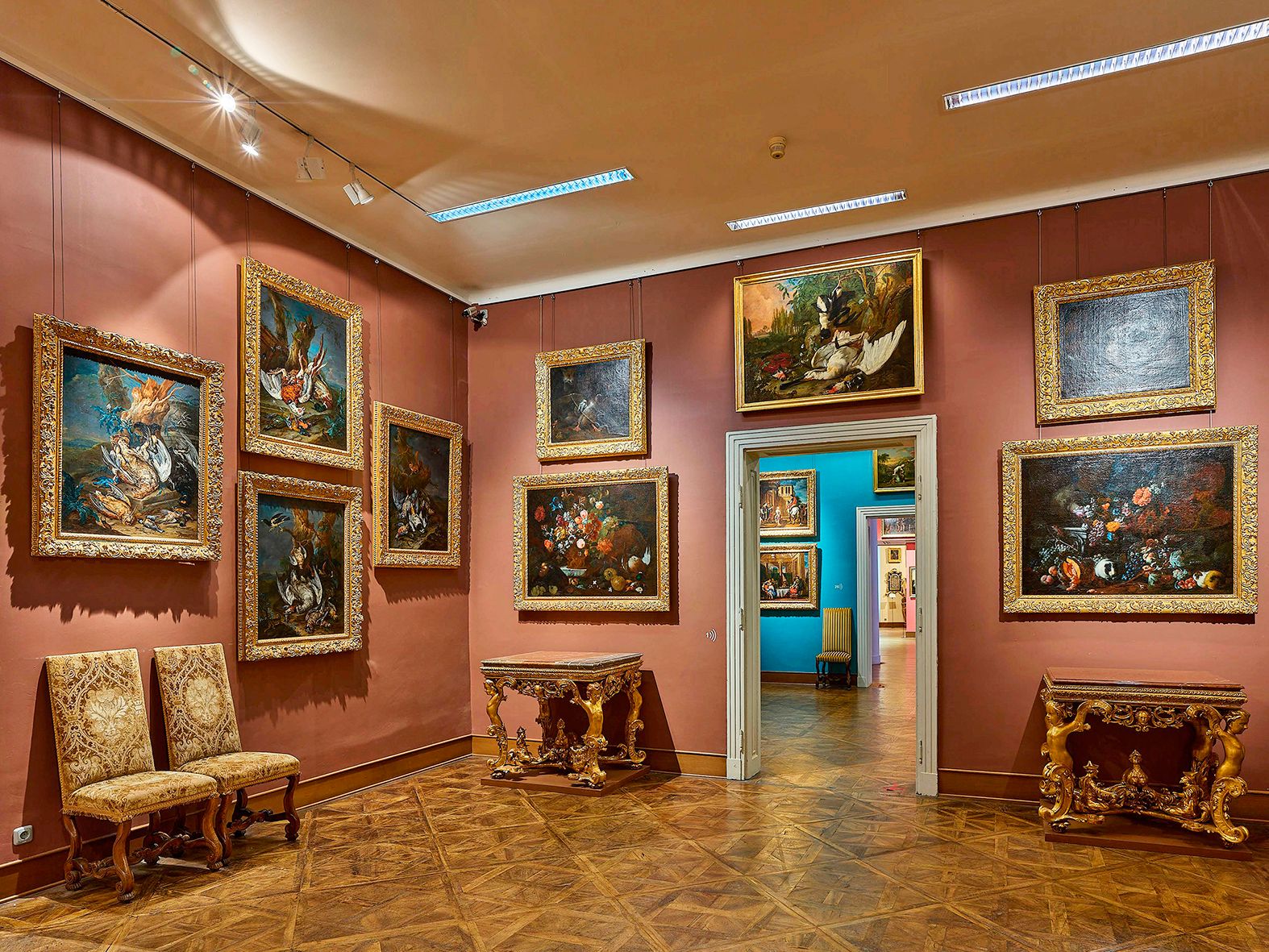 Ein Raum im Museum mit Gemälden an den Wänden und antiken Möbeln.