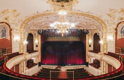 Das Stadttheater Berndorf strahlt eine elegante Atmosphäre aus, die die Vorfreude auf unvergessliche Aufführungen weckt. Die kunstvoll gestaltete Decke und die opulente Beleuchtung verleihen dem Raum einen Hauch von Magie, während die roten Samtvorhänge auf den großen Moment warten. Hier wird Kultur lebendig und lädt Besucher ein, in die Welt des Theaters einzutauchen.