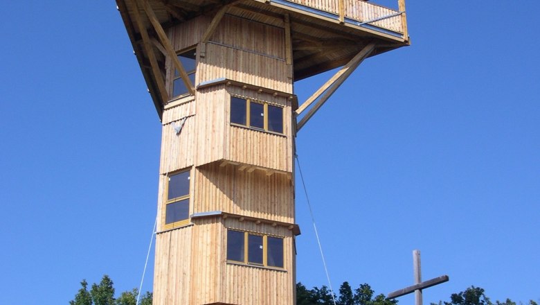 Holzturm Buchbergwarte mit Kreuz daneben, blauer Himmel.