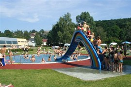 Kinder spielen auf einer bunten Rutsche im Freibad.