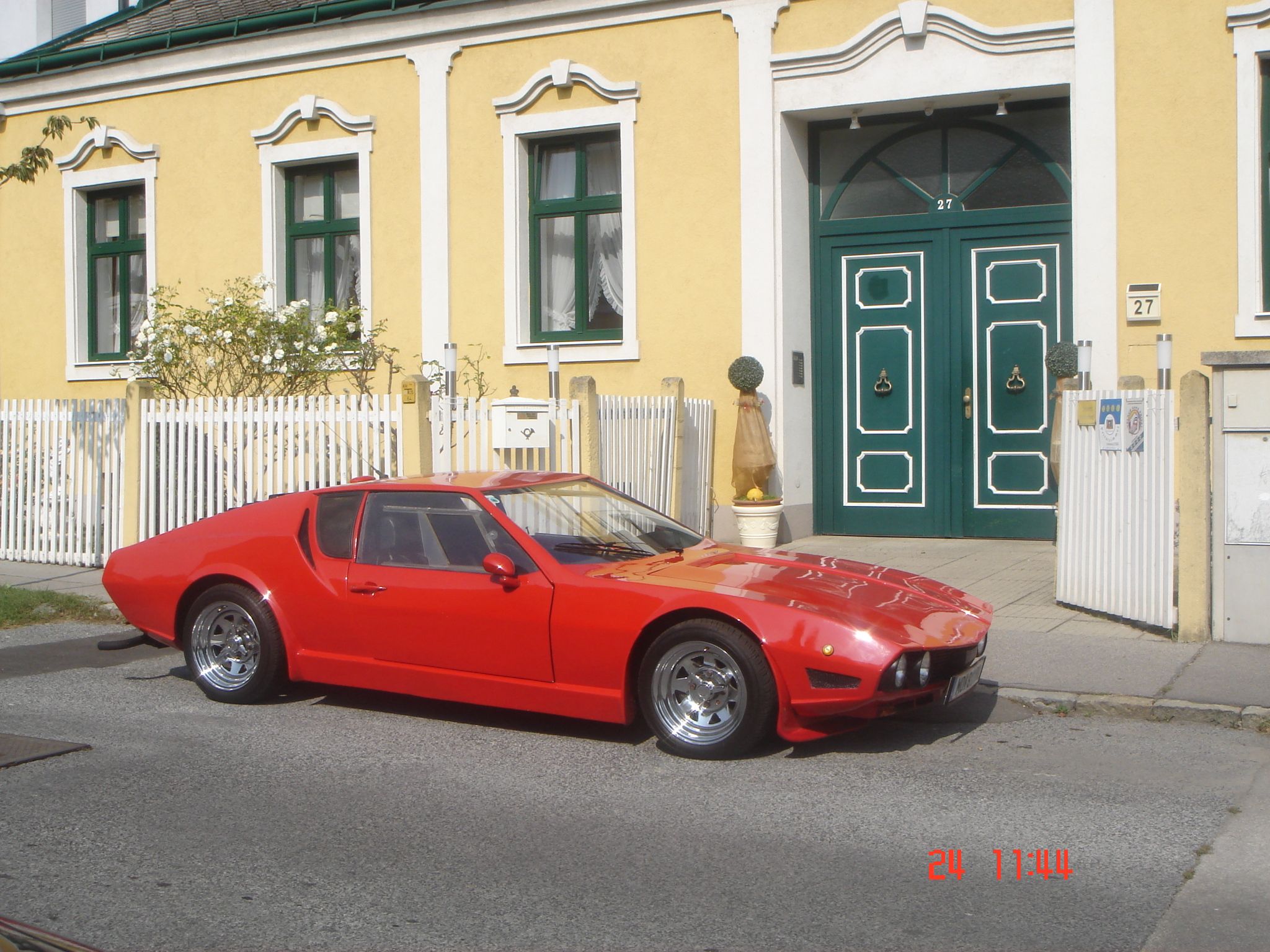Gelbes Gebäude mit grüner Tür und rotem Auto.