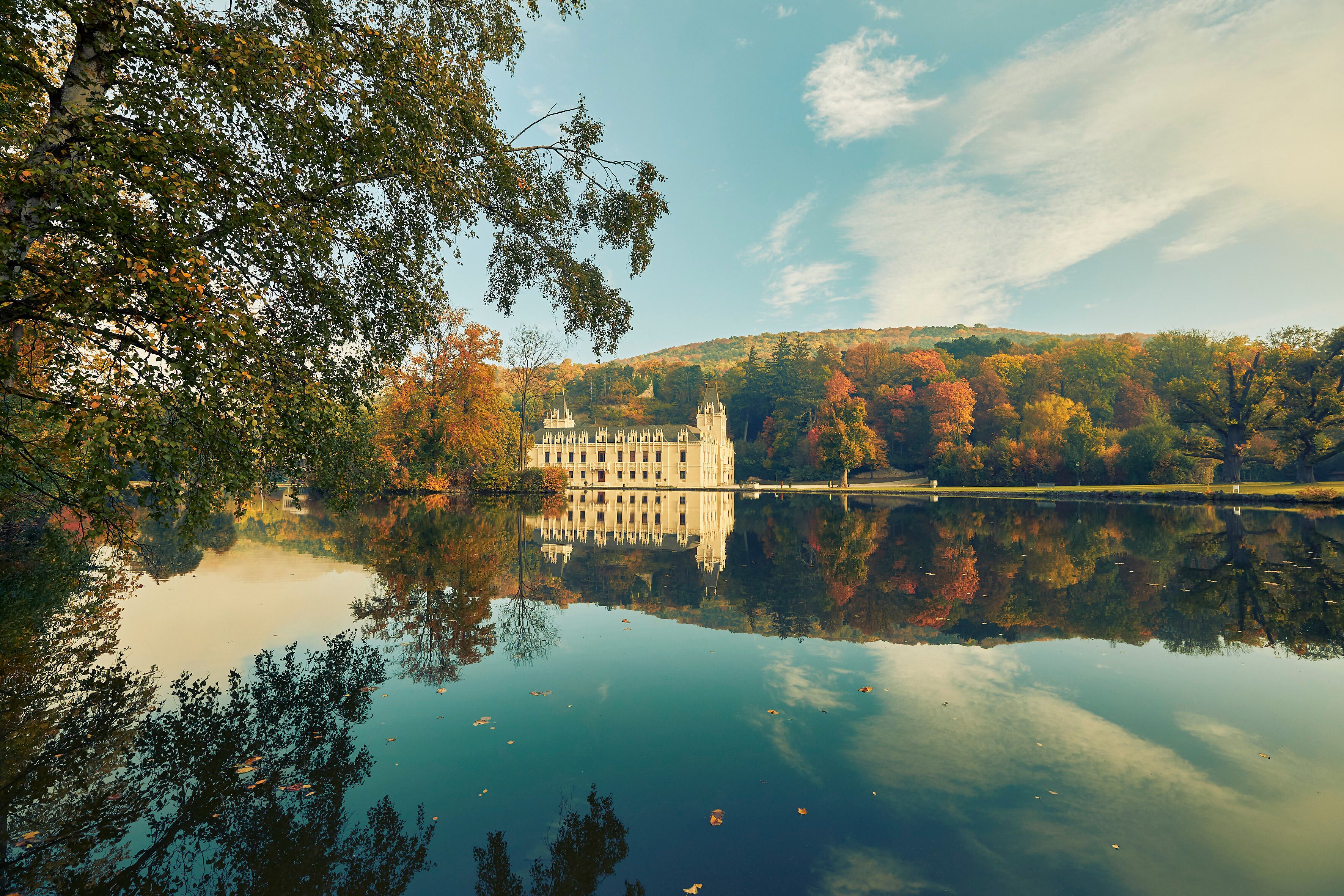 Umgeben von bunten Herbstblättern spiegelt sich das majestätische Schloss Hernstein friedlich im klaren Wasser des Sees. Die sanften Hügel im Hintergrund laden zu einem entspannten Spaziergang ein, während die frische Luft die Sinne belebt.