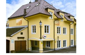 Gelbes Hotelgebäude mit mehreren Fenstern und einem Schild mit der Aufschrift 'Hotel Perchtoldsdorf'.