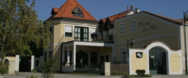 Ein traditionelles Gebäude mit gelber Fassade und rotem Ziegeldach, beschriftet mit 'Winzerhof zum Wald'.