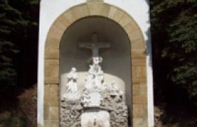 Eine kleine Kapelle mit einem Kreuz und religi&ouml;sen Figuren in einer Nische.