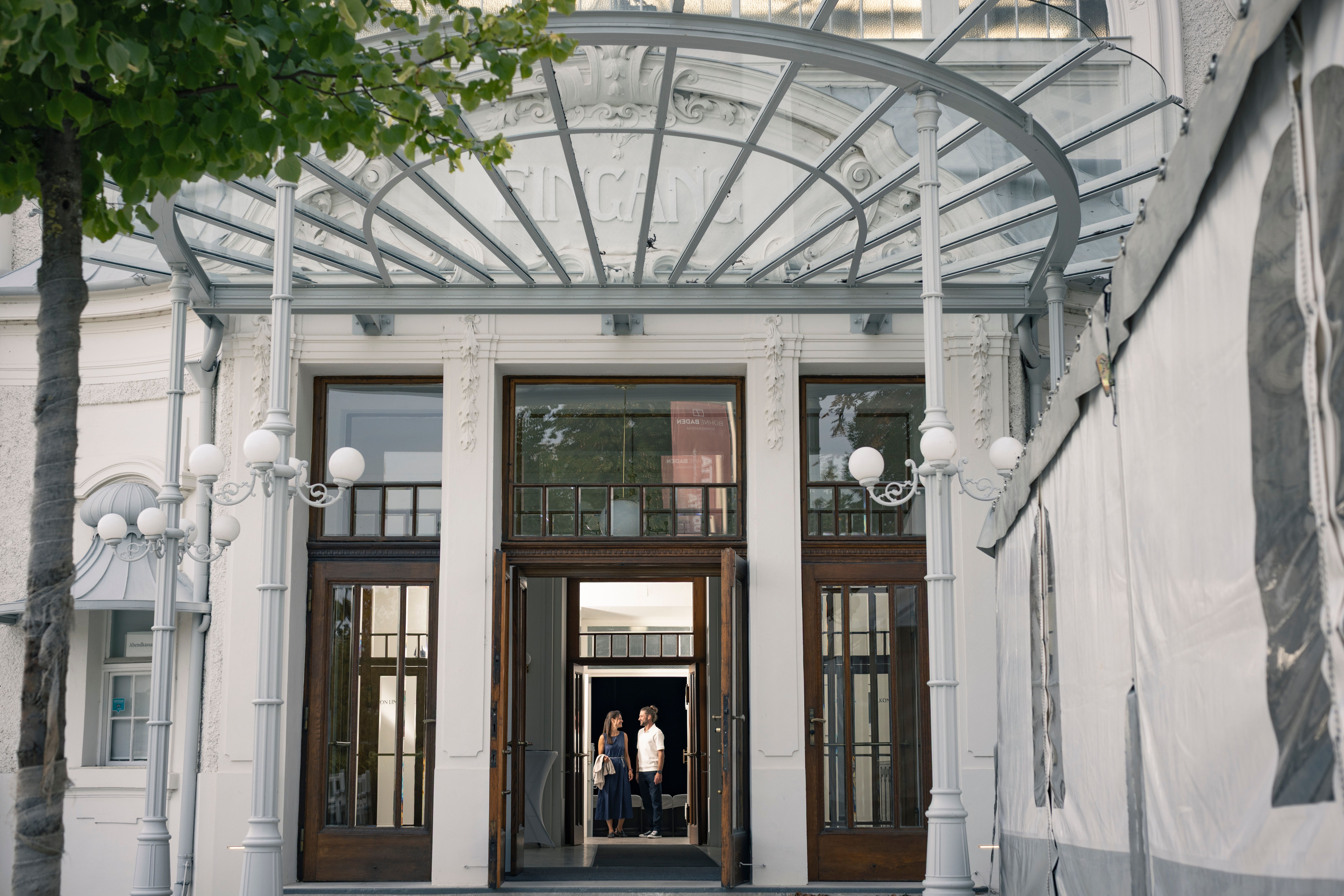 Ein Paar verlässt nach einer Veranstaltung die historische Sommerarena Baden, ein beeindruckendes Bauwerk. 