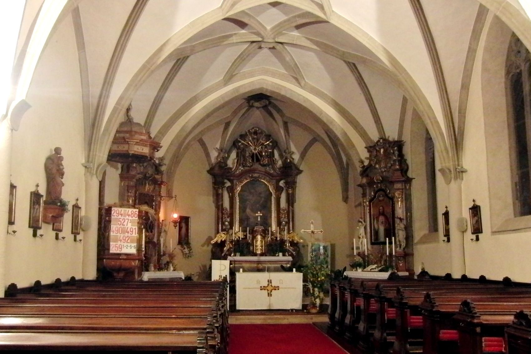 Innenansicht einer Kirche mit Altar und Bänken.