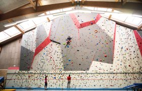 Kletterhalle mit Kletterwand und Personen beim Klettern.