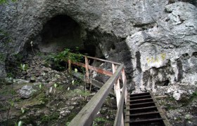 Entrance to a cave with wooden stairs and railings.