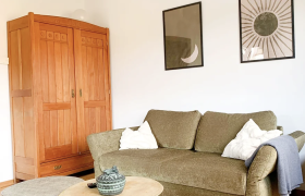 green sofa in room with wooden floor and wardrobe