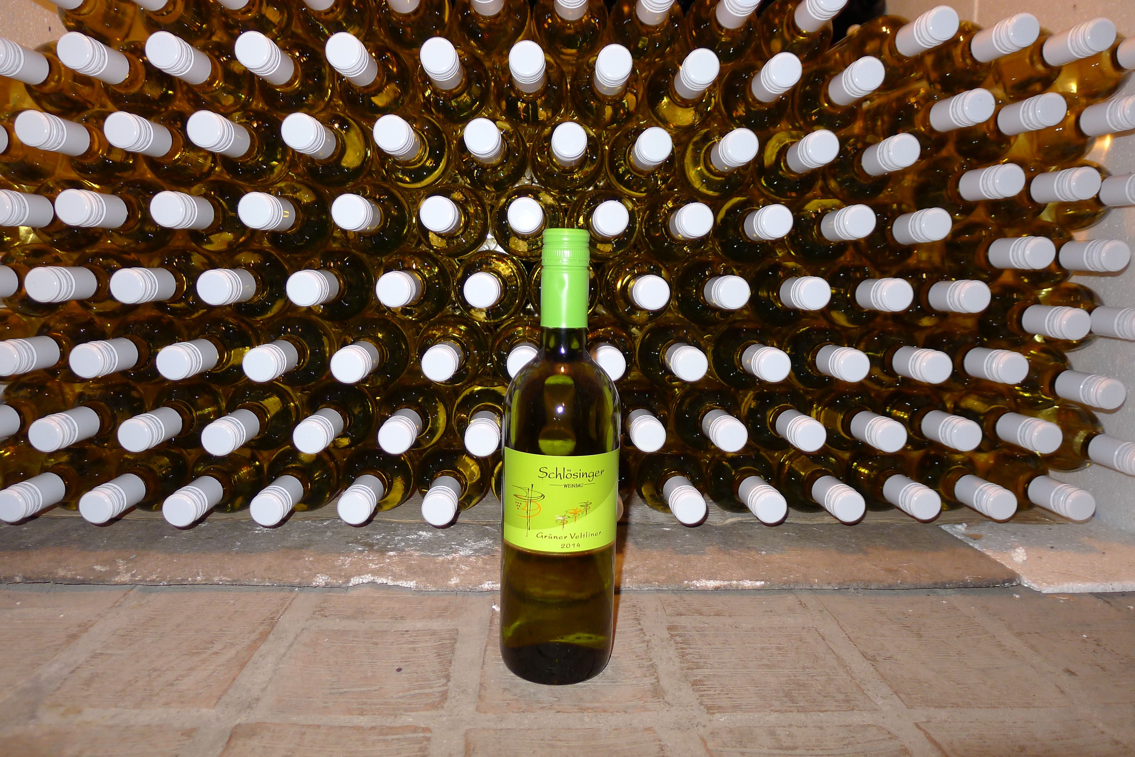 Eine Flasche Grüner Veltliner vor einem Regal voller Weinflaschen.