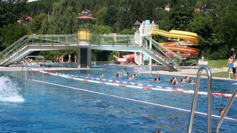 Freibad mit Schwimmern, Rutsche und Brücke im Wienerwaldbad Purkersdorf.