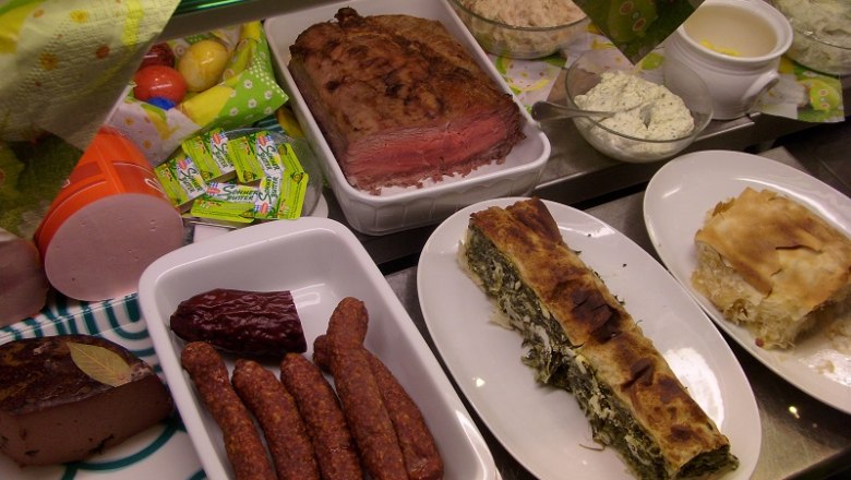 Verschiedene Speisen auf einem Buffet, darunter Fleisch, Würste und Strudel.