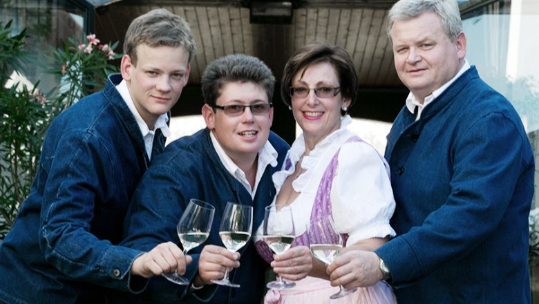 Four people in traditional dress clink glasses of wine.