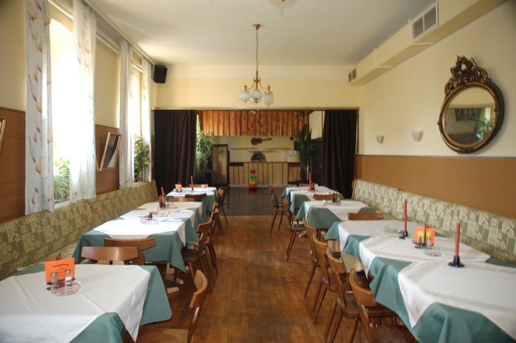 Ein traditionelles Gasthaus mit Holzboden, gedeckten Tischen und einem Kronleuchter.