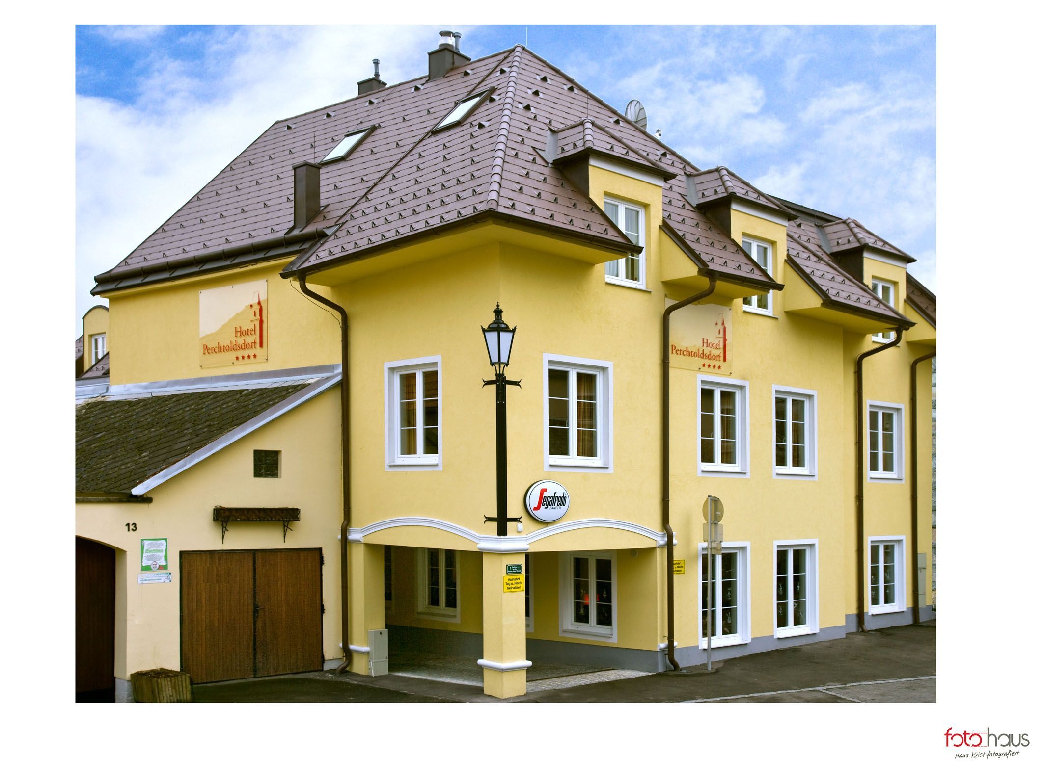 Gelbes Hotelgebäude mit mehreren Fenstern und einem Schild mit der Aufschrift 'Hotel Perchtoldsdorf'.