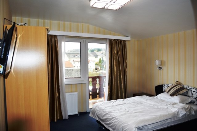 A hotel room with a double bed, window with curtains and a view of the building outside.