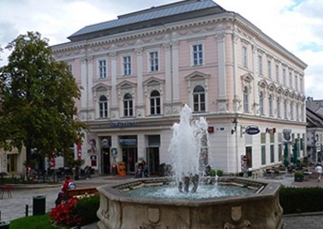 Historisches Gebäude mit Brunnen im Vordergrund.