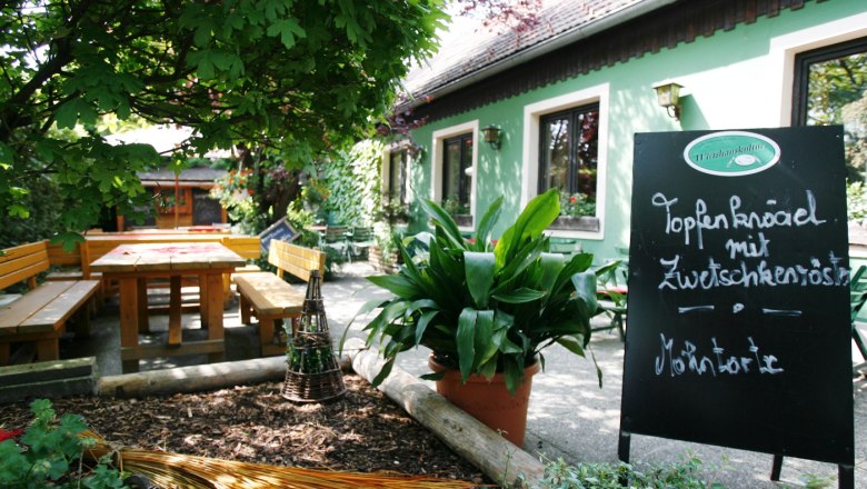 Gem&uuml;tlicher Gastgarten mit Holzb&auml;nken und Tafel im Wirtshaus Bonka, Wienerwald.