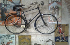 Old bicycle on a wall with vintage advertising posters in the Vösendorf Castle Bicycle Museum.