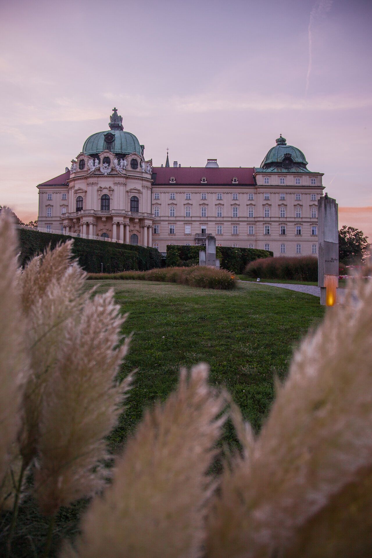 Die sanften Hügel und die majestätische Architektur verleihen der Umgebung eine zauberhafte Atmosphäre. In der Dämmerung erstrahlt das Gebäude in warmen Farben und lädt dazu ein, die Schönheit der Natur und Kultur zu genießen. Ein idealer Ort, um die Seele baumeln zu lassen und die malerische Landschaft zu erkunden.
