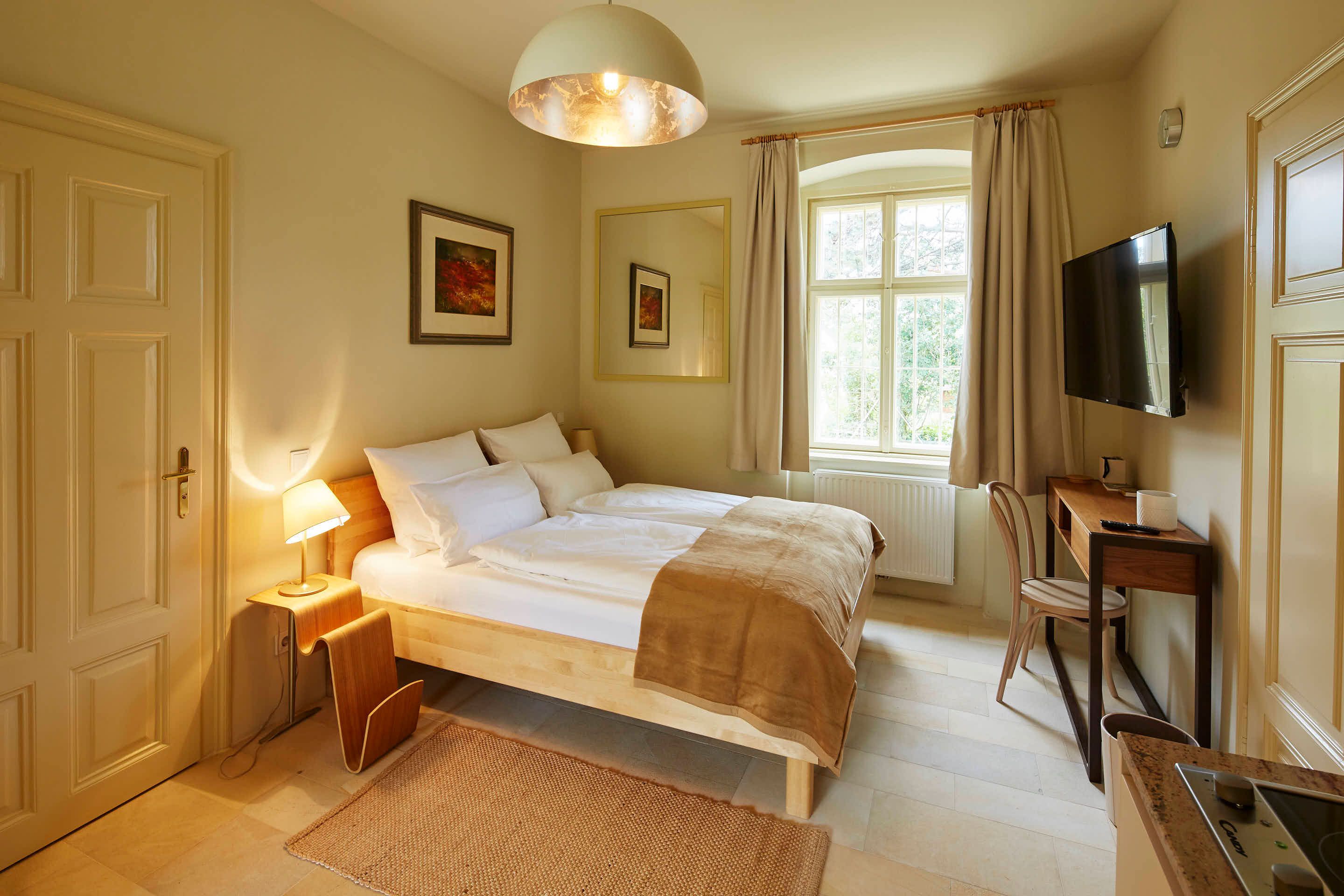 Gemütliches Schlafzimmer mit Doppelbett, Schreibtisch und großem Fenster.