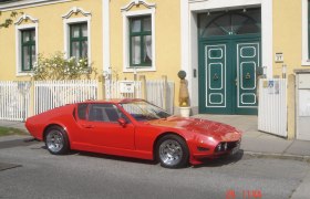 Gelbes Gebäude mit grüner Tür und rotem Auto.