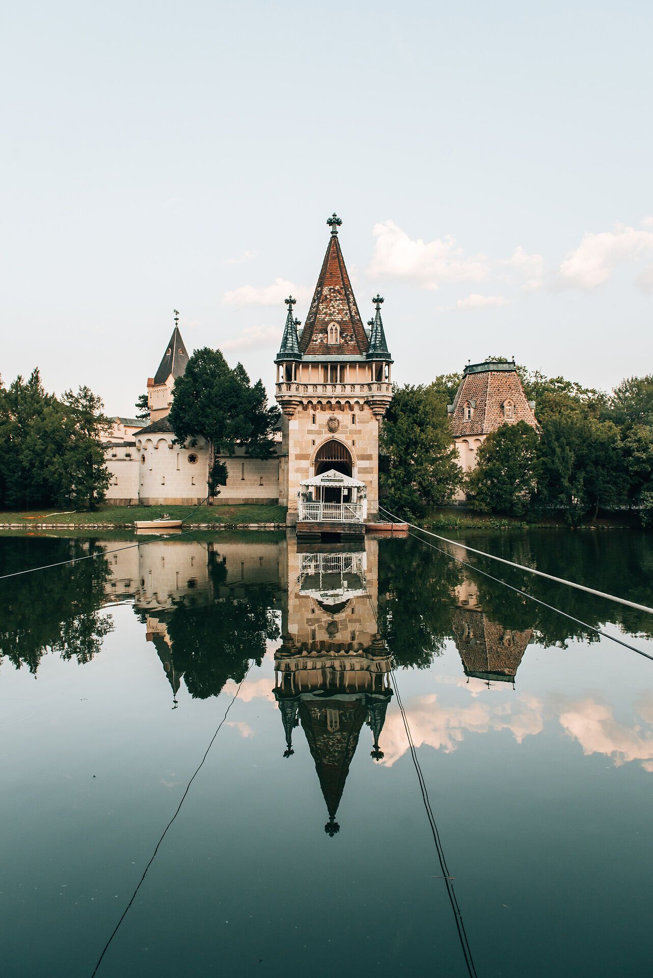 Die malerische Kulisse des Schlosses spiegelt sich sanft im ruhigen Wasser des Teiches wider. Umgeben von üppigem Grün und blühenden Pflanzen, lädt dieser Ort zum Verweilen und Entspannen ein. Hier, wo Geschichte und Natur harmonisch verschmelzen, erleben Besucher die Schönheit der Sommerfrische.