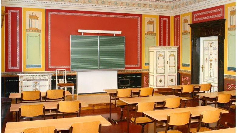 Klassenzimmer im Berndorfer Stil mit antikem Dekor und Holzmöbeln.