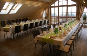 A festively decorated hall with long tables and chairs in a country inn.