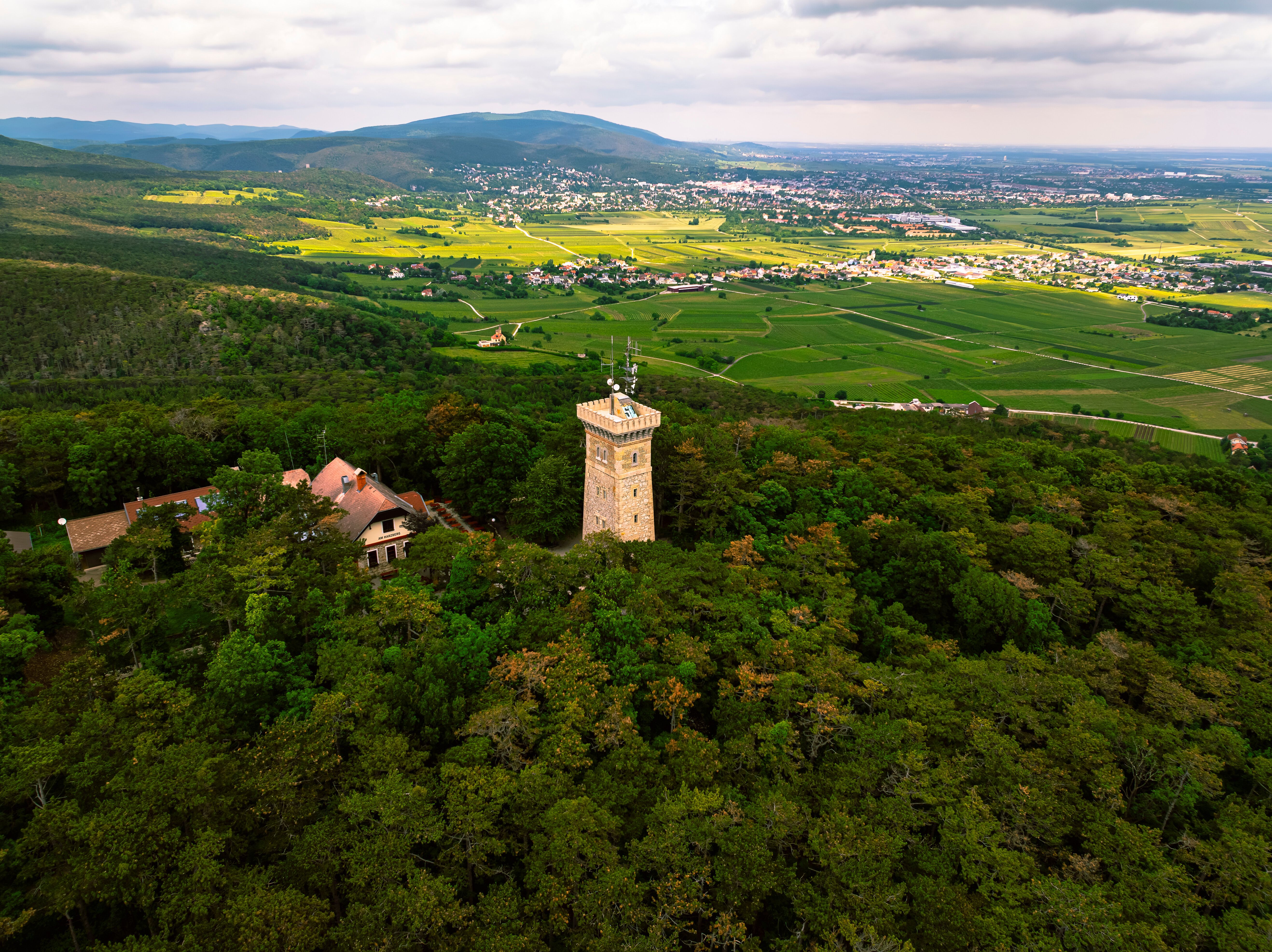 Umgeben von üppigen Wäldern und sanften Hügeln, erhebt sich der majestätische Aussichtsturm und bietet einen atemberaubenden Blick über die malerische Landschaft. Die frische Bergluft und das Zwitschern der Vögel laden dazu ein, die Schönheit der Natur in vollen Zügen zu genießen.