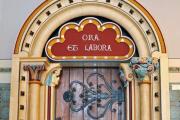 Verzierte Holztür mit lateinischer Inschrift 'Ora et Labora'.