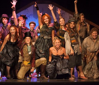 Theatergruppe in bunten Kostümen auf der Bühne des Stadttheaters Mödling.