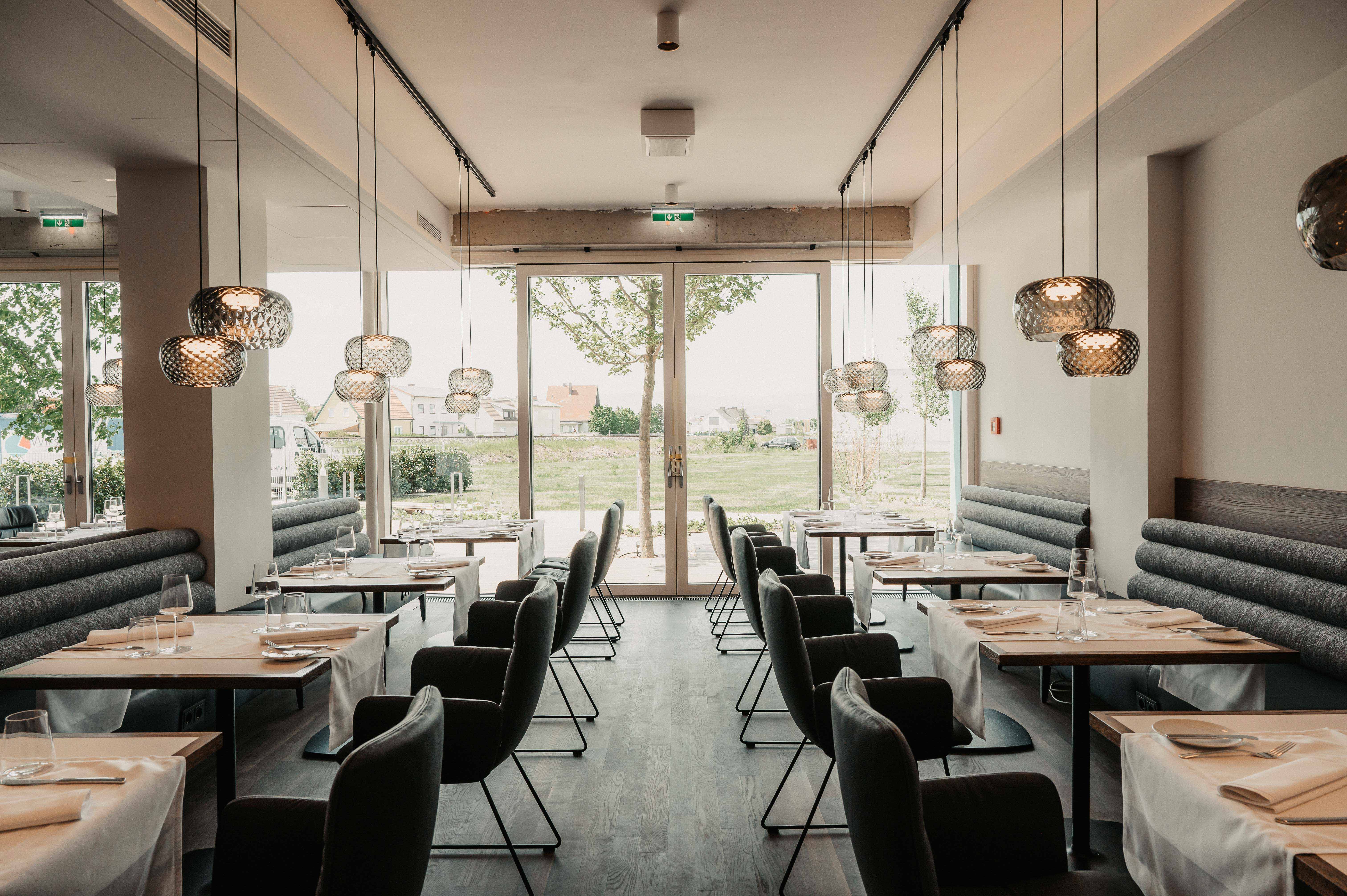 Modernes Restaurant mit eleganter Einrichtung und großen Fenstern.
