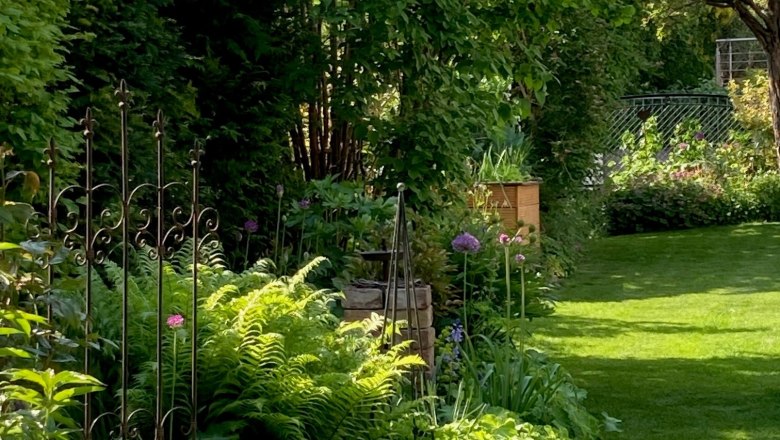 A well-kept garden with lush greenery, flowers and a small fence.