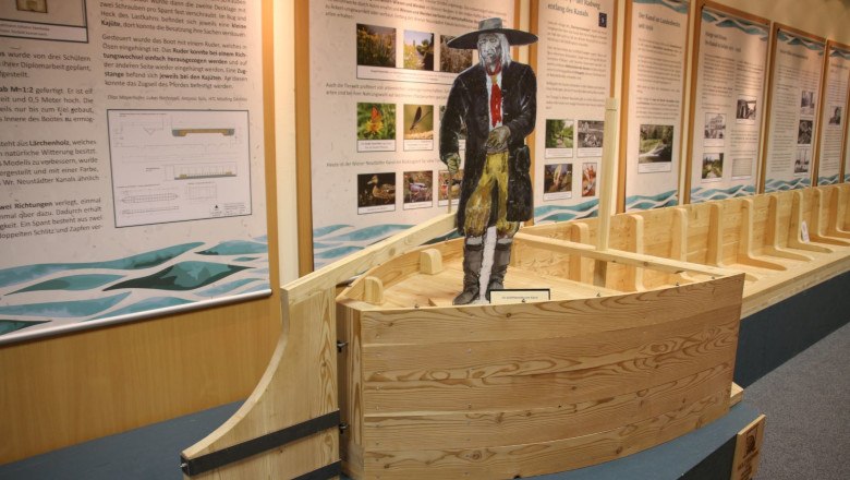 Ausstellung im Museum Traiskirchen mit Holzboot und Figur eines Mannes in traditioneller Kleidung.
