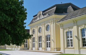Historisches Gebäude mit gelber Fassade und großen Fenstern im Sonnenschein.