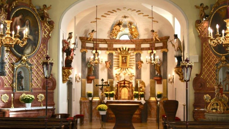 Innenraum einer reich verzierten Kirche mit Altar und Statuen.