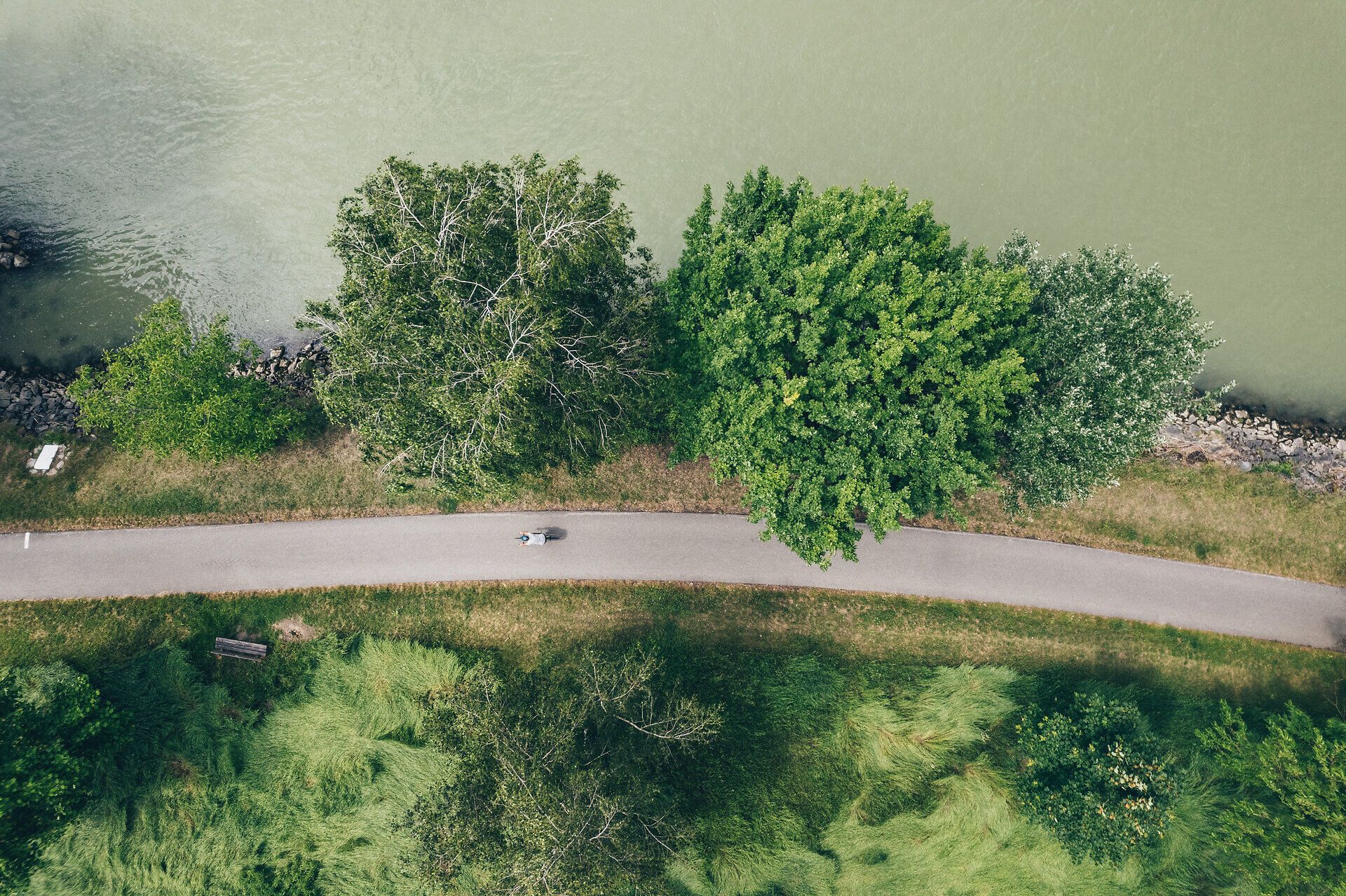 Ein malerischer Radweg schlängelt sich entlang der sanften Ufer der Donau, umgeben von üppigem Grün und majestätischen Bäumen. Die ruhige Atmosphäre lädt dazu ein, die Schönheit der Natur zu genießen und die frische Luft zu atmen. Hier, wo der Fluss sanft fließt, wird jeder Moment zu einem unvergesslichen Erlebnis.