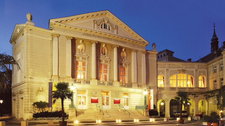 Das Stadttheater Baden bei Nacht, beleuchtet mit warmem Licht.
